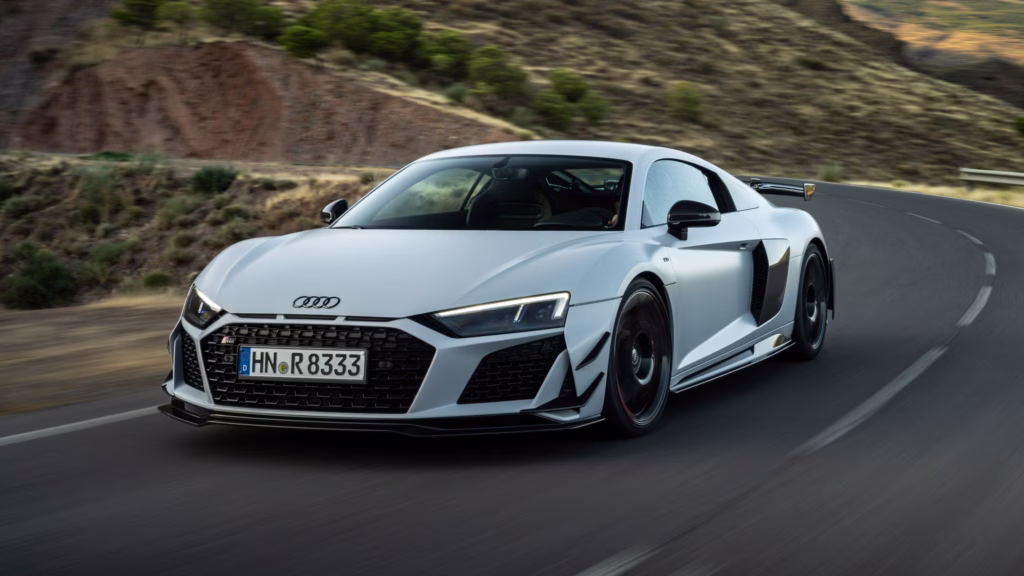A white Audi R8 driving on a mountain road